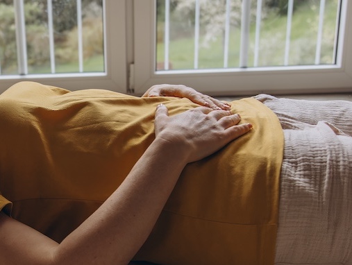 Femme allongée, une main posée sur le ventre